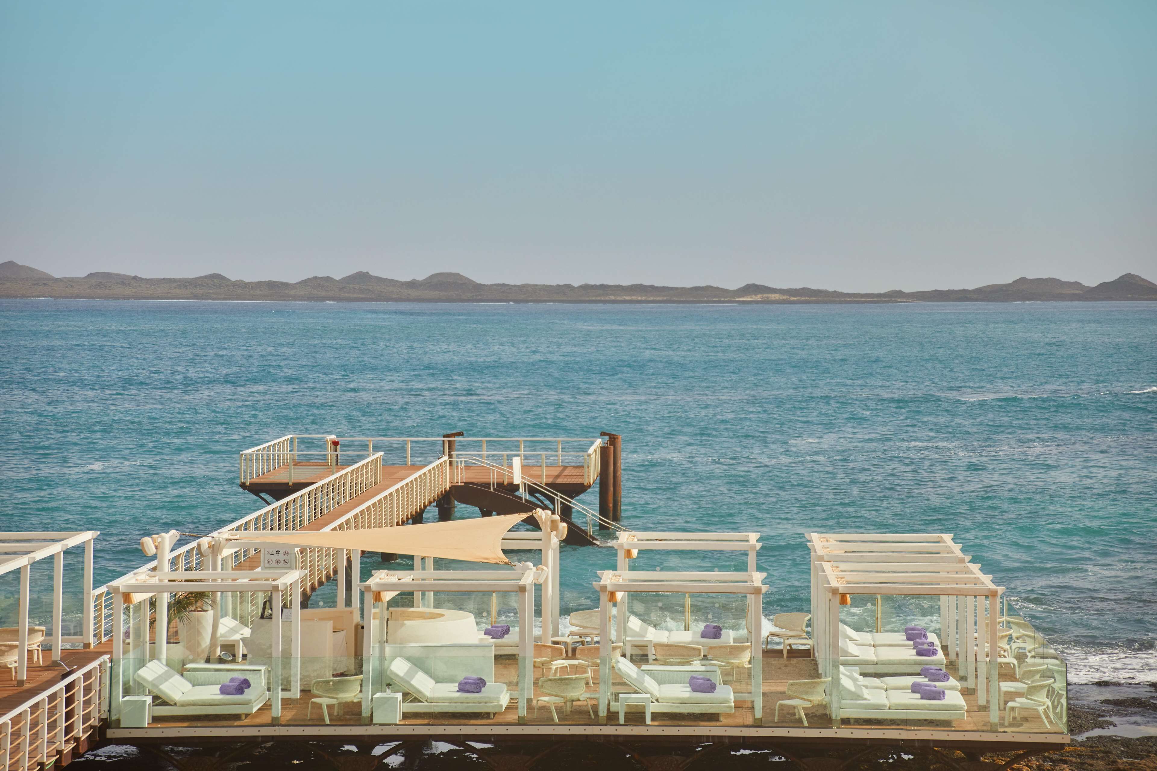 A deck with lounge chairs and a staircase leading to a higher deck.