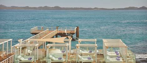 A deck with lounge chairs and a staircase leading to a higher deck.