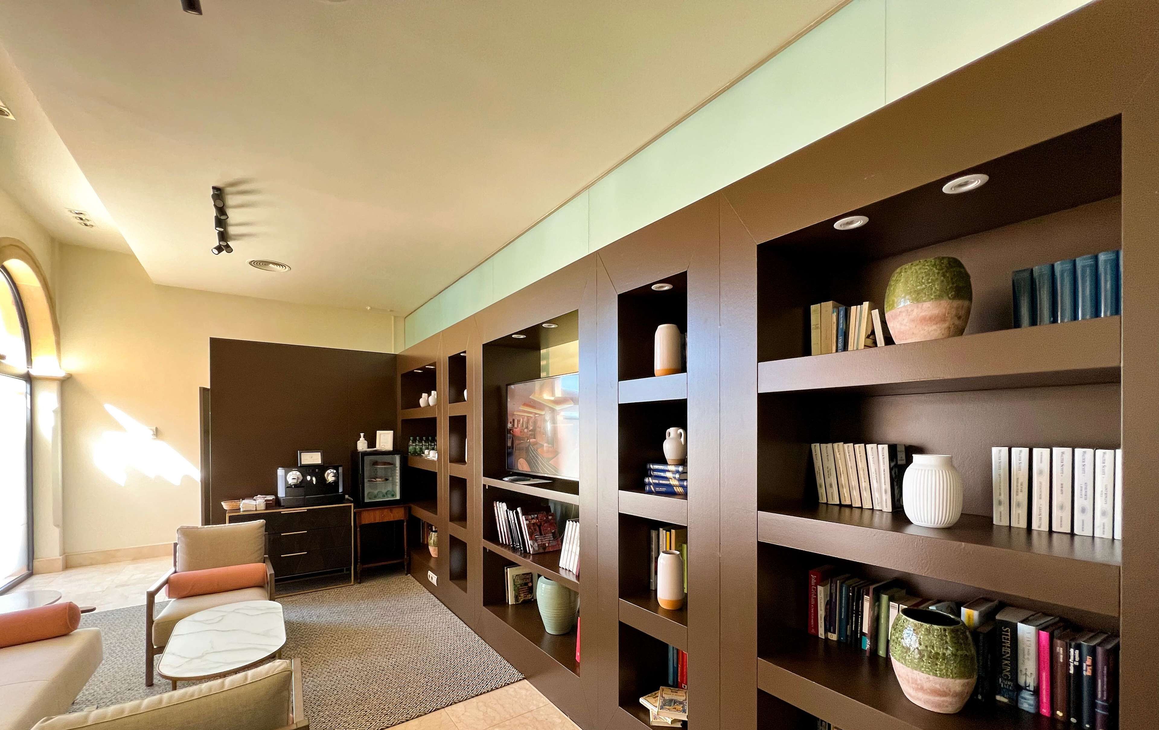 Ein modernes Wohnzimmer mit einer großen Bücherwand, einem Fernseher und einer Sitzecke mit Tisch und Stühlen.
