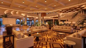 A spacious lobby with a central seating area, multiple tables, and a patterned floor.