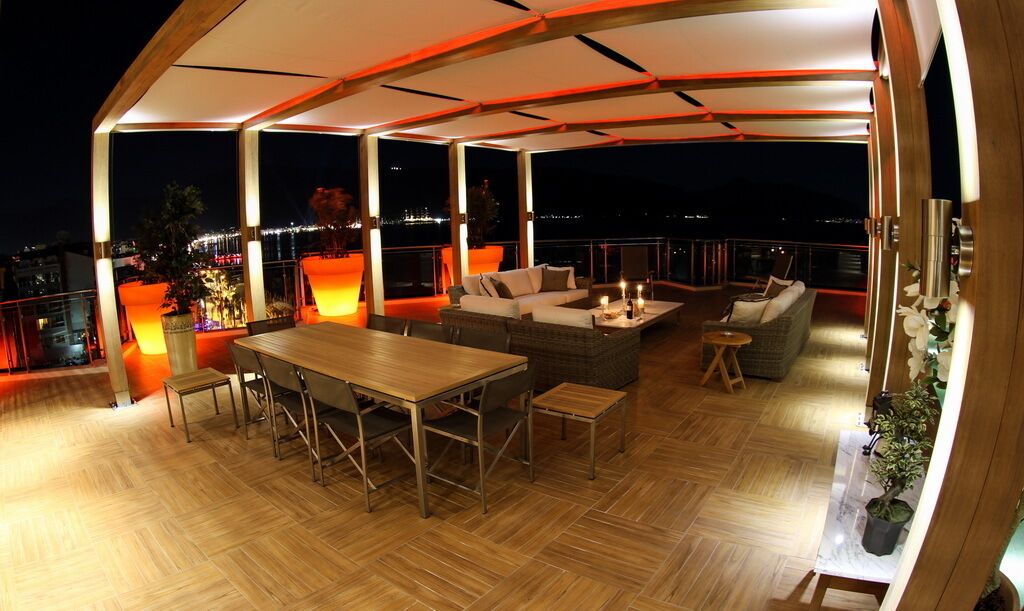 An outdoor patio with a wooden table and chairs, a sofa, and a small coffee table.