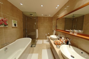 Un baño moderno con una bañera grande, dos lavamanos y una ducha con cerramiento de vidrio.