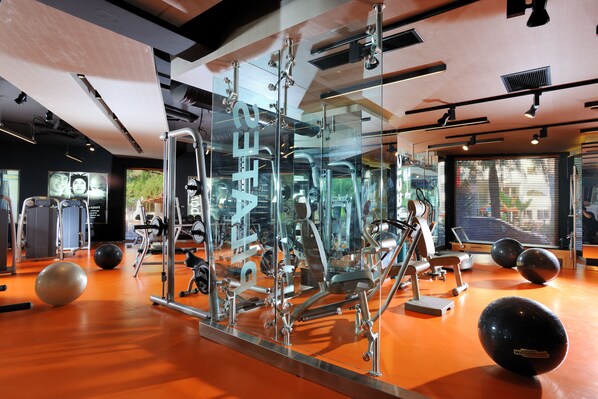 A gym with exercise equipment, a mirrored wall, and a large window.
