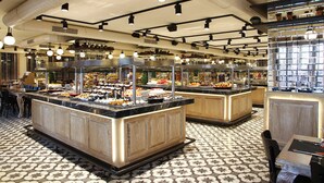 A buffet area with multiple food stations, a patterned floor, and a modern ceiling design.