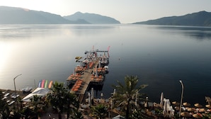 A pier extending into calm water with a view of distant mountains.