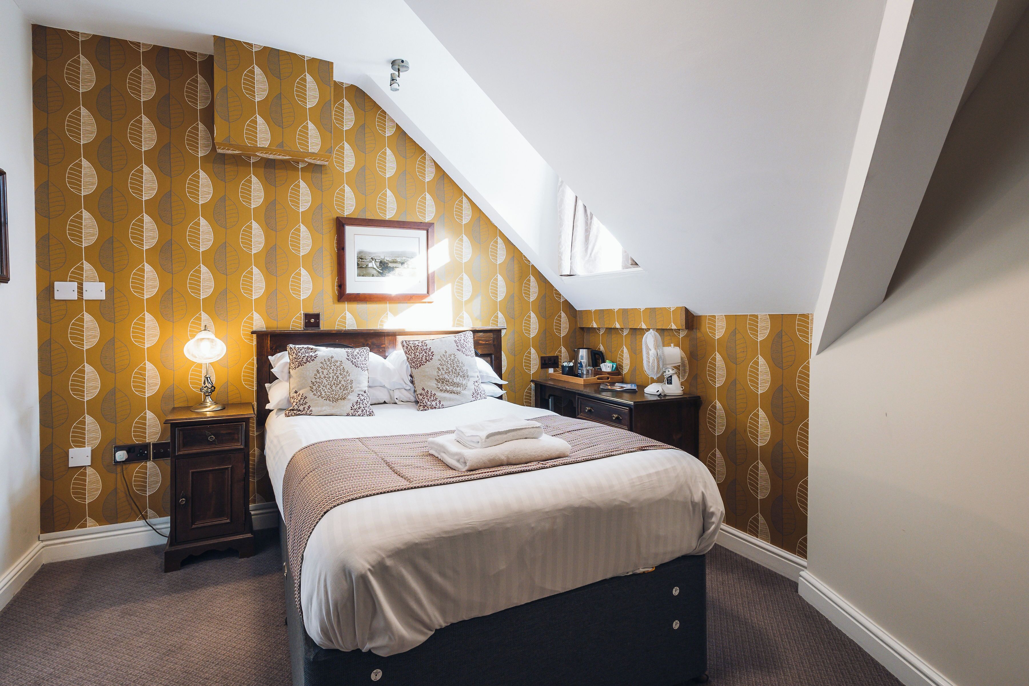A bedroom with a bed, nightstands, a lamp, and a picture on the wall.