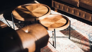 A wooden coffee table with a round top and a smaller round table beside it, both with metal legs. - White Lion Royal Hotel (Bala)