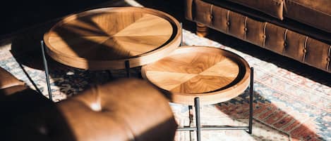A wooden coffee table with a round top and a smaller round table beside it, both with metal legs.