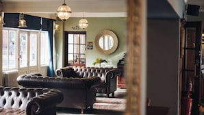A room with leather sofas, a mirror, and a door with a sign. - White Lion Royal Hotel (Bala)