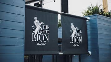 Dos banderines negros con texto blanco y un logo de león, colgados de una estructura azul.