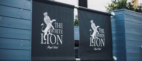 Two black banners with white text and a lion logo, hanging on a blue structure.