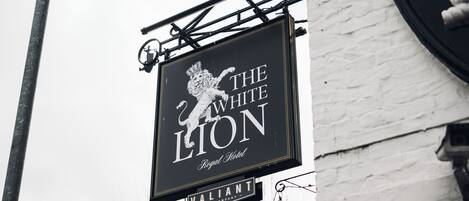 A black sign with white lettering for "The White Lion Royal Hotel" and "Valiant Pub Company" below it.