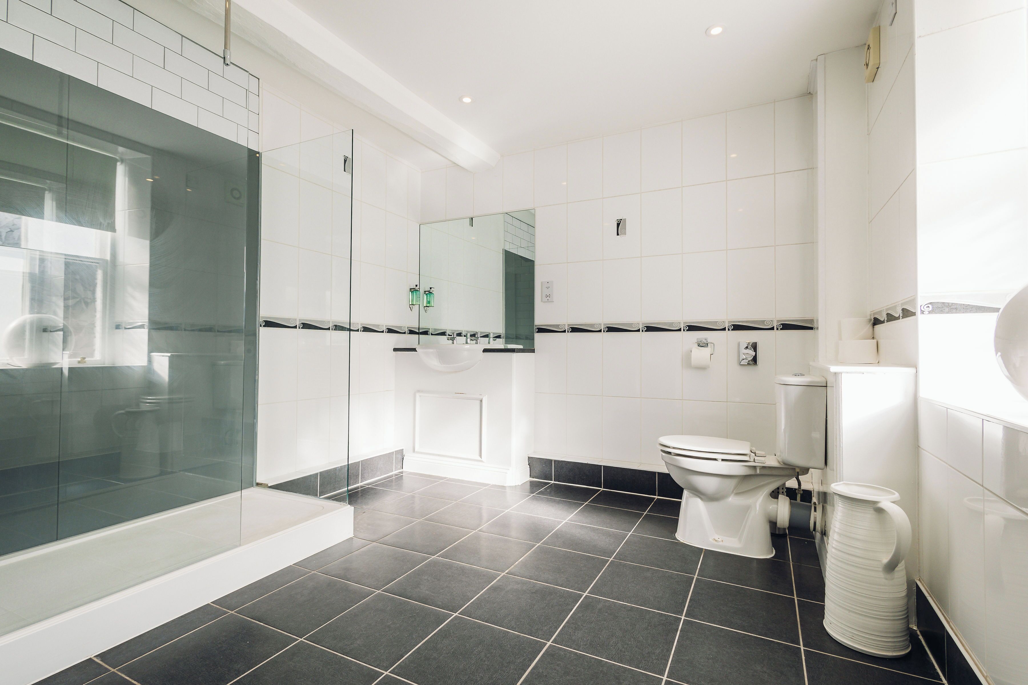 Un baño moderno con ducha acristalada, inodoro y lavamanos.