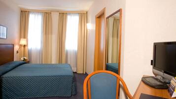 Una habitación de hotel con dos camas, un escritorio con computadora y una silla.