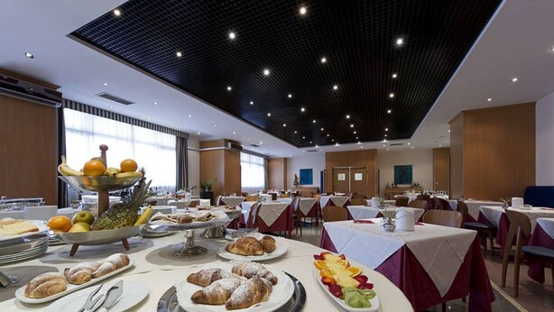 A spacious dining area with multiple tables, a fruit display, and a variety of pastries. - Classic Hotel Tulipano (Terni)