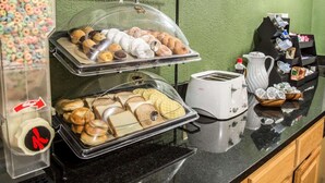 A breakfast buffet with various pastries, muffins, and bread, a coffee machine, and a toaster. - Rodeway Inn & Suites Plymouth Hwy 64 (Plymouth)
