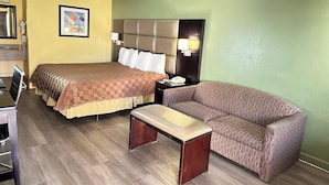 A hotel room with a bed, a couch, a desk, and a nightstand. - Rodeway Inn & Suites Plymouth Hwy 64 (Plymouth)