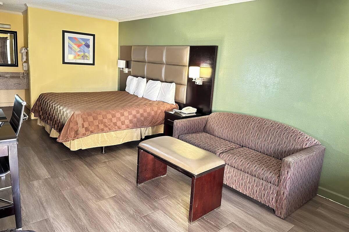 Ein Hotelzimmer mit Bett, einer Sitzecke, einem Schreibtisch und einem Nachttisch.
