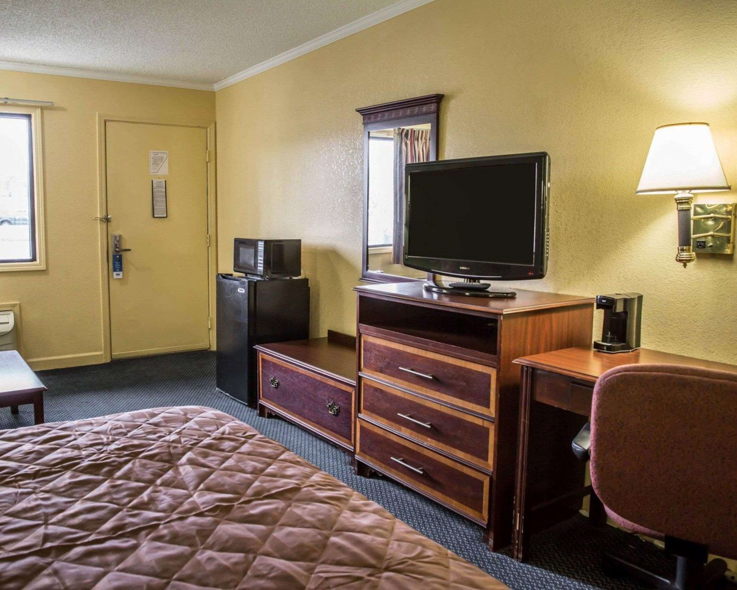 A hotel room with a bed, a desk with a television, a microwave, and a coffee maker.