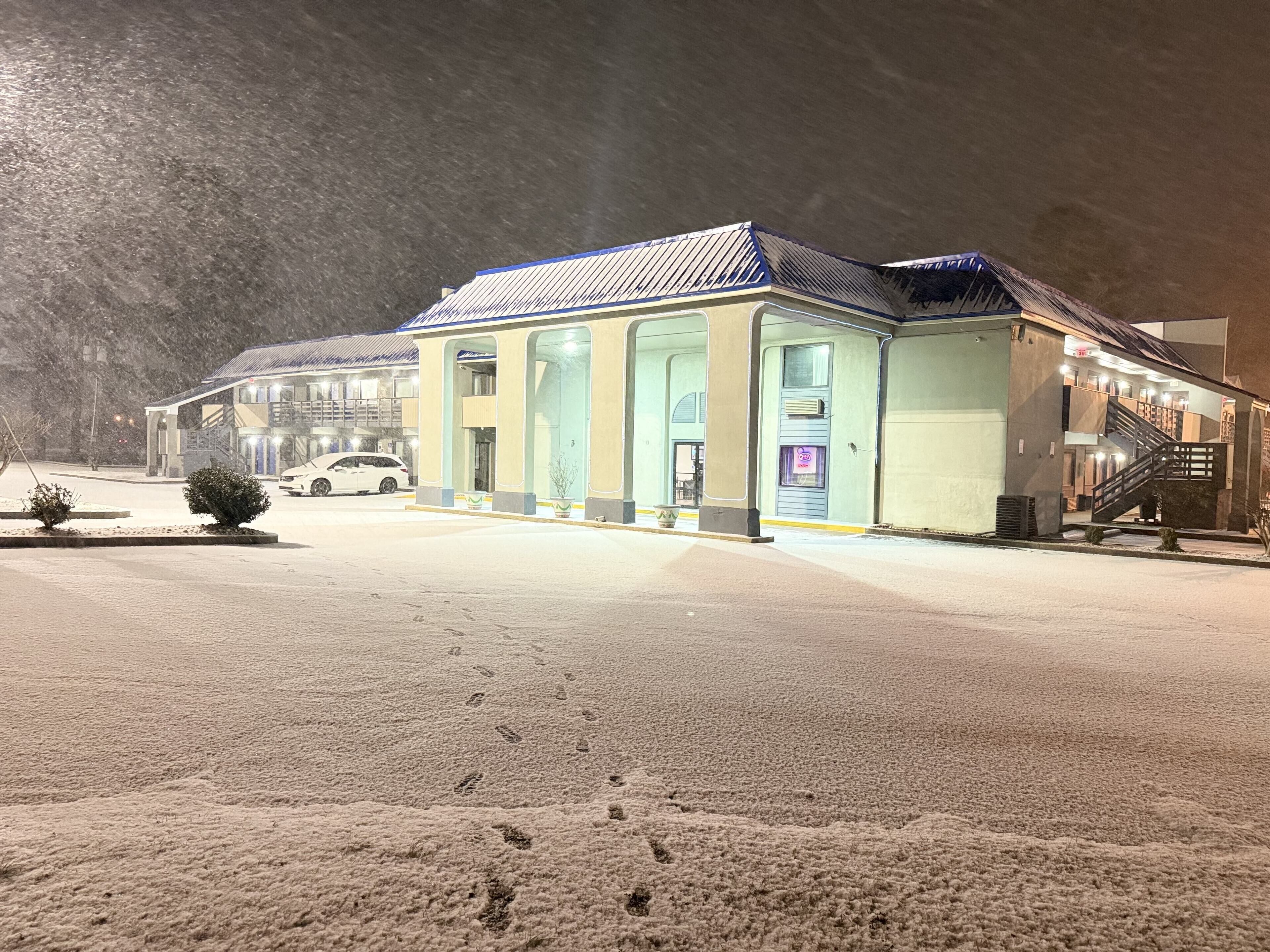 A hotel with a snow-covered parking lot and a single-story building with a flat roof.
