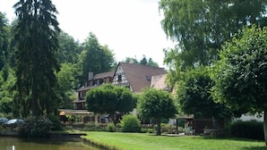 A traditional half-timbered house with a pond in the foreground. - Auberge d'Imsthal (La Petite-Pierre)