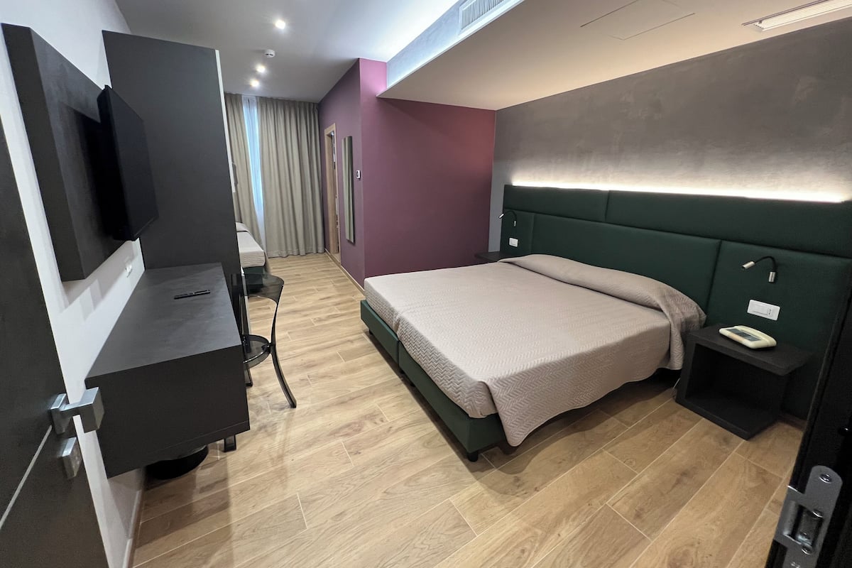 Una habitación de hotel moderna con cama, mesita de noche y televisor de pantalla plana montado en la pared.