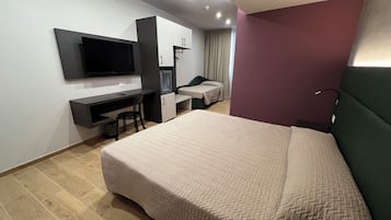 Ein modernes Hotelzimmer mit einem großen Bett, einem Schreibtisch mit Stuhl, einem Fernseher und einem Kleiderschrank.