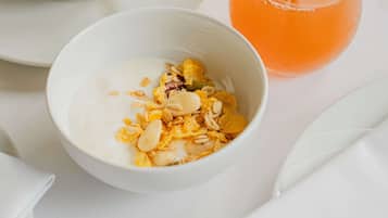 Un desayuno con una taza de café, un vaso de jugo de naranja, tostadas y un tazón de cereal con nueces.