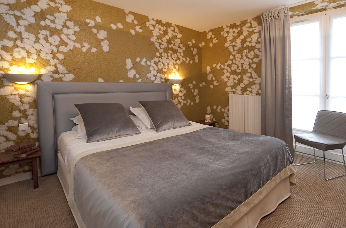 Ein Hotelzimmer mit einem großen Bett, zwei Nachttischlampen, einem Sessel und einem Heizkörper.