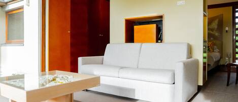 A modern living room with a white sofa, a glass coffee table, and a wooden side table.