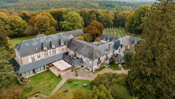 Un grand immeuble à étages, à l’architecture symétrique, entouré d’une végétation luxuriante et situé dans un paysage vallonné.