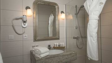A bathroom with a sink, mirror, robe, and shower.