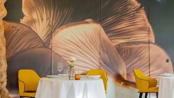 A dining area with a table set for two, yellow chairs, and a large wall mural.