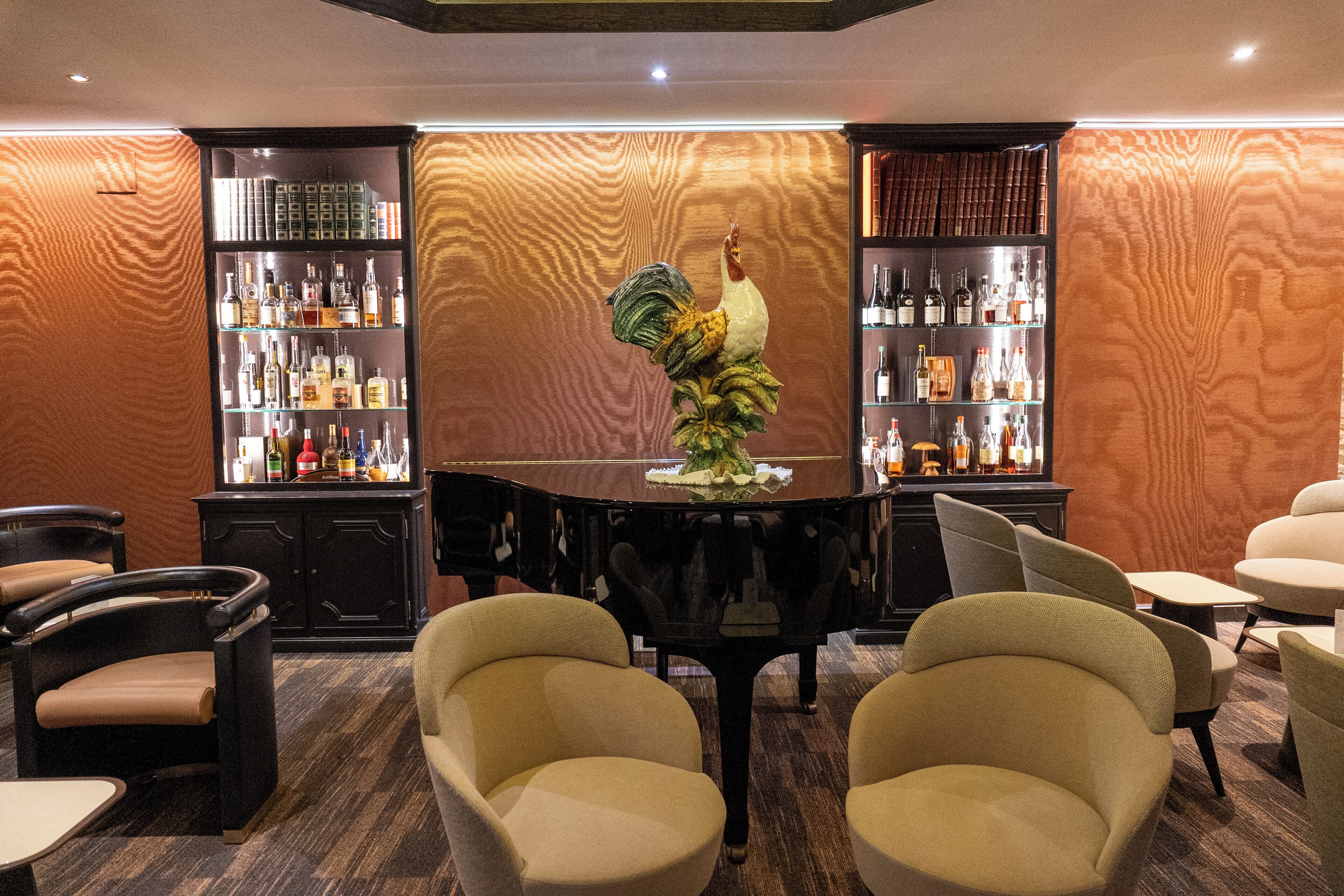 Eine Bar mit Klavier, Stühlen und Regalen voller Spirituosenflaschen.