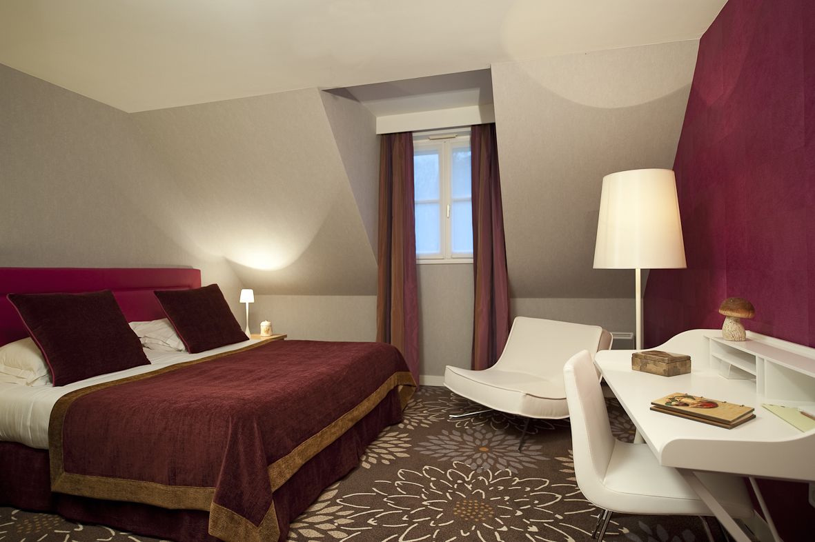Una camera d'albergo con un letto grande, una scrivania con una lampada e una sedia.