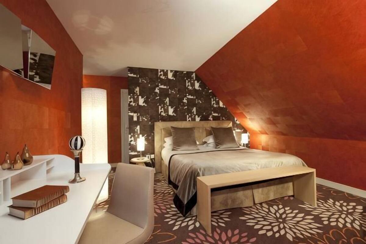 Een moderne slaapkamer met een bed, nachtkastje, stoel en een grote spiegel.