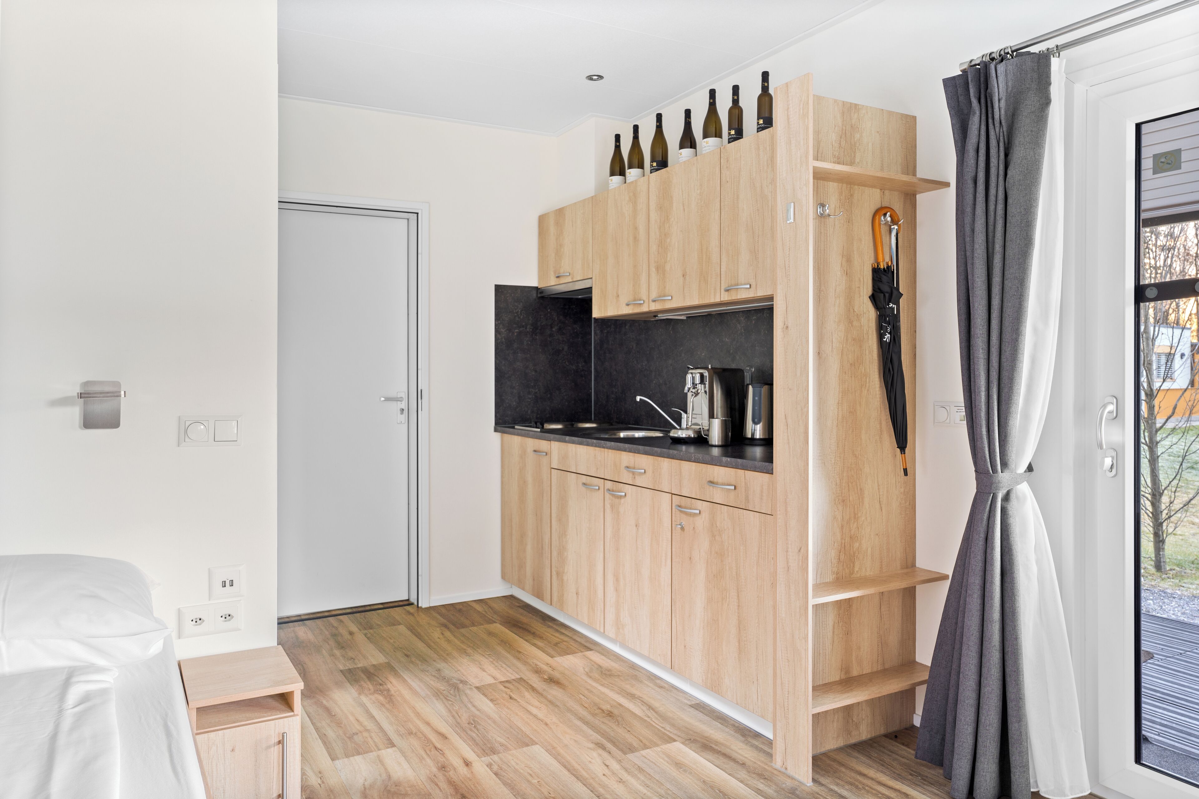 Eine moderne Küche mit Holzschränken, einer schwarzen Arbeitsplatte und einem Weinkühlschrank.