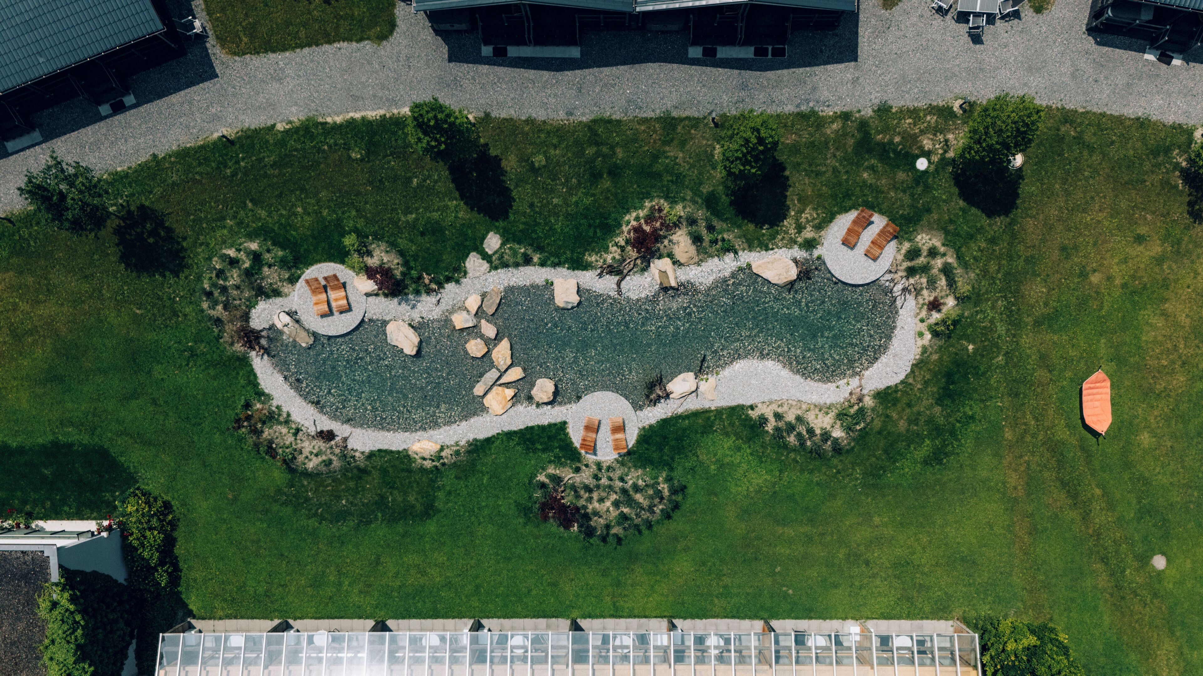 An aerial view of a landscaped area with a central water feature, surrounded by seating areas and pathways.