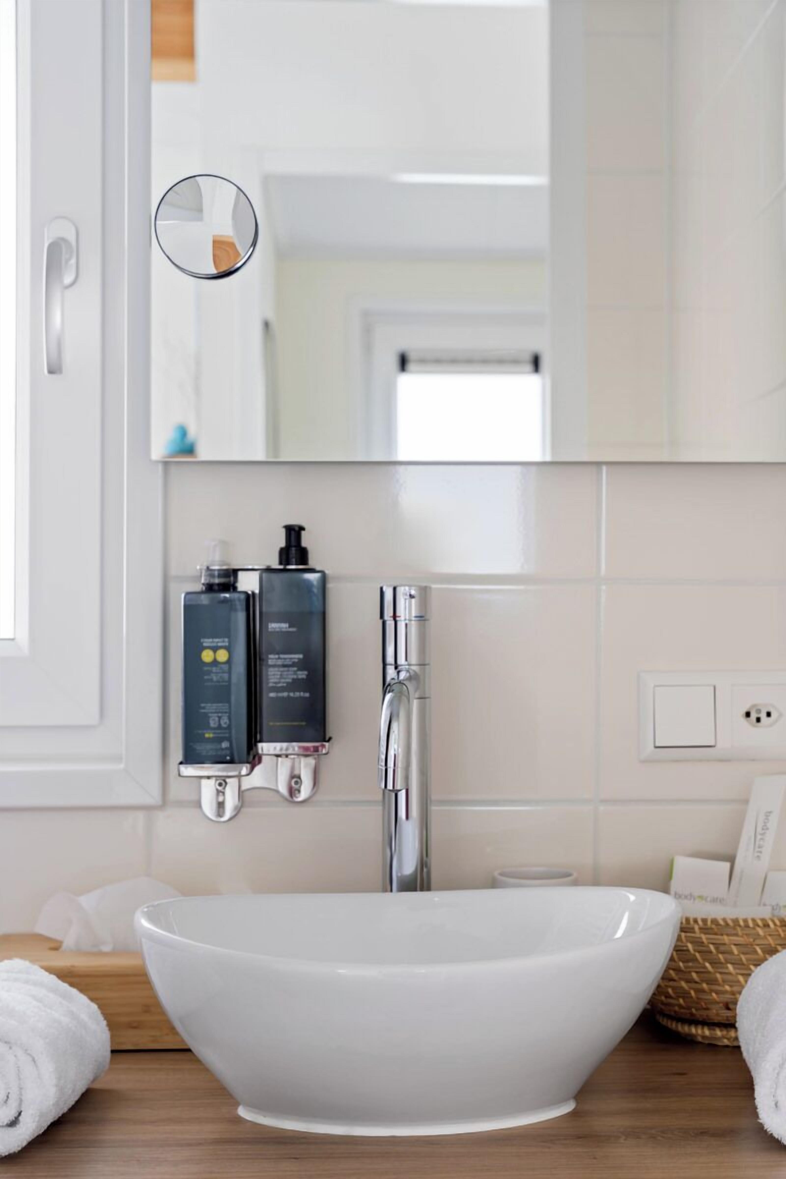Une salle de bain moderne avec un lavabo blanc, un miroir et deux articles de toilette.