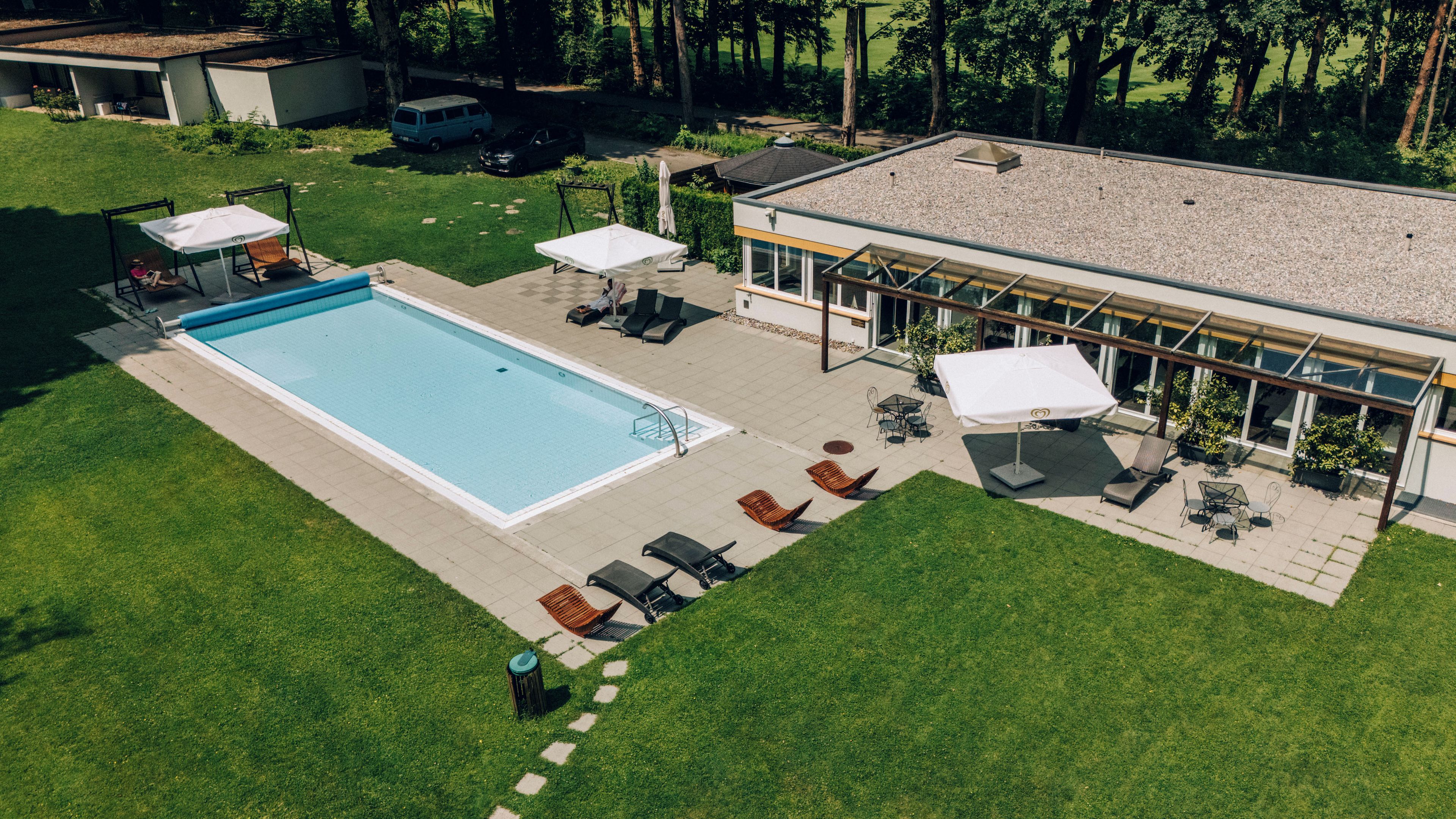 Un área de piscina en la azotea con piscina, sillas de descanso y sombrillas.