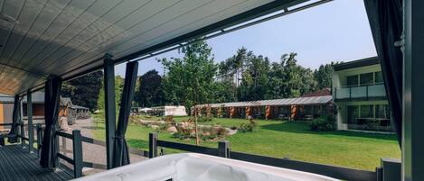 Zona de hidromasaje con vistas a un jardín ajardinado y un edificio al fondo.