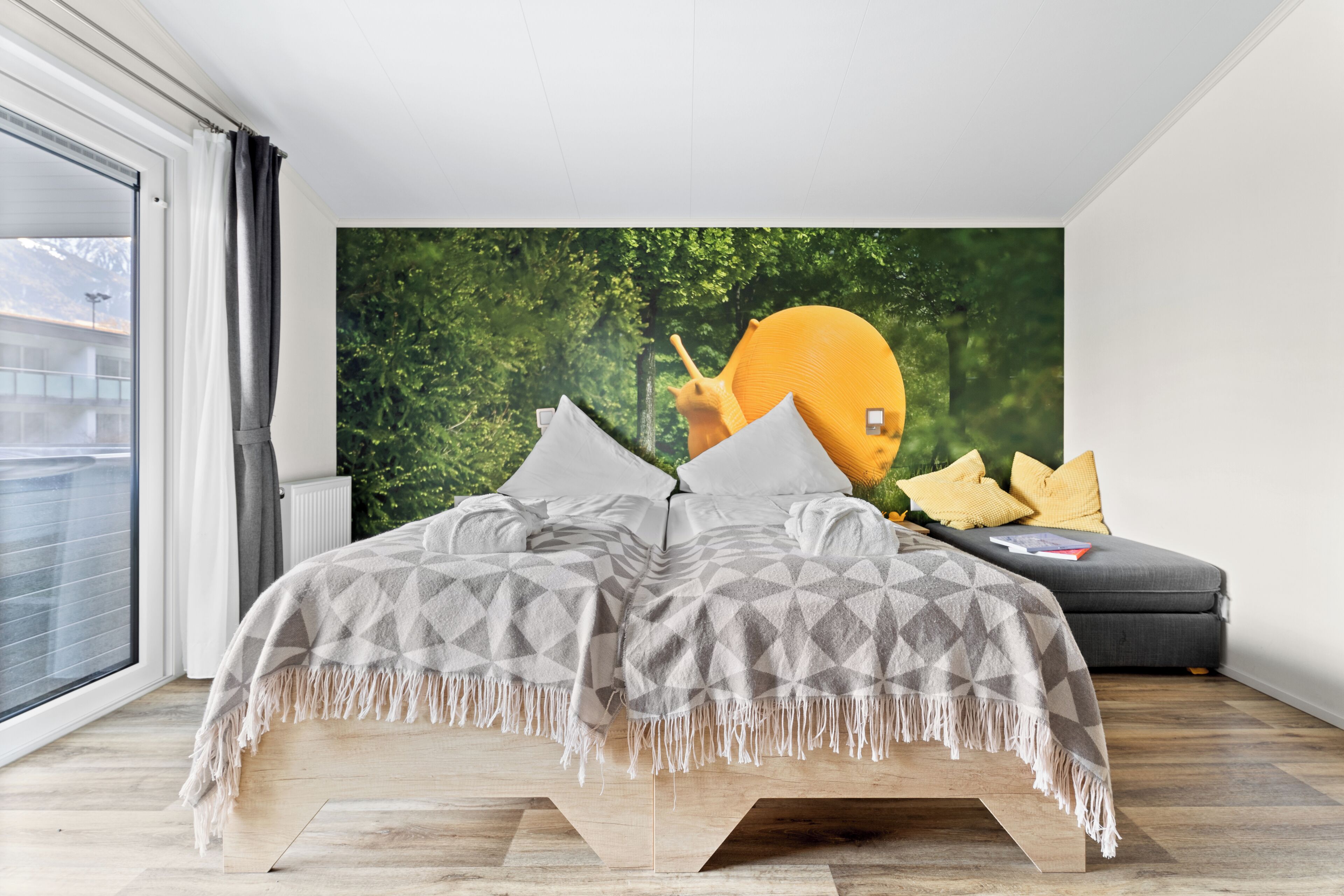 A modern bedroom with a large bed, a sofa, and a wall mural.