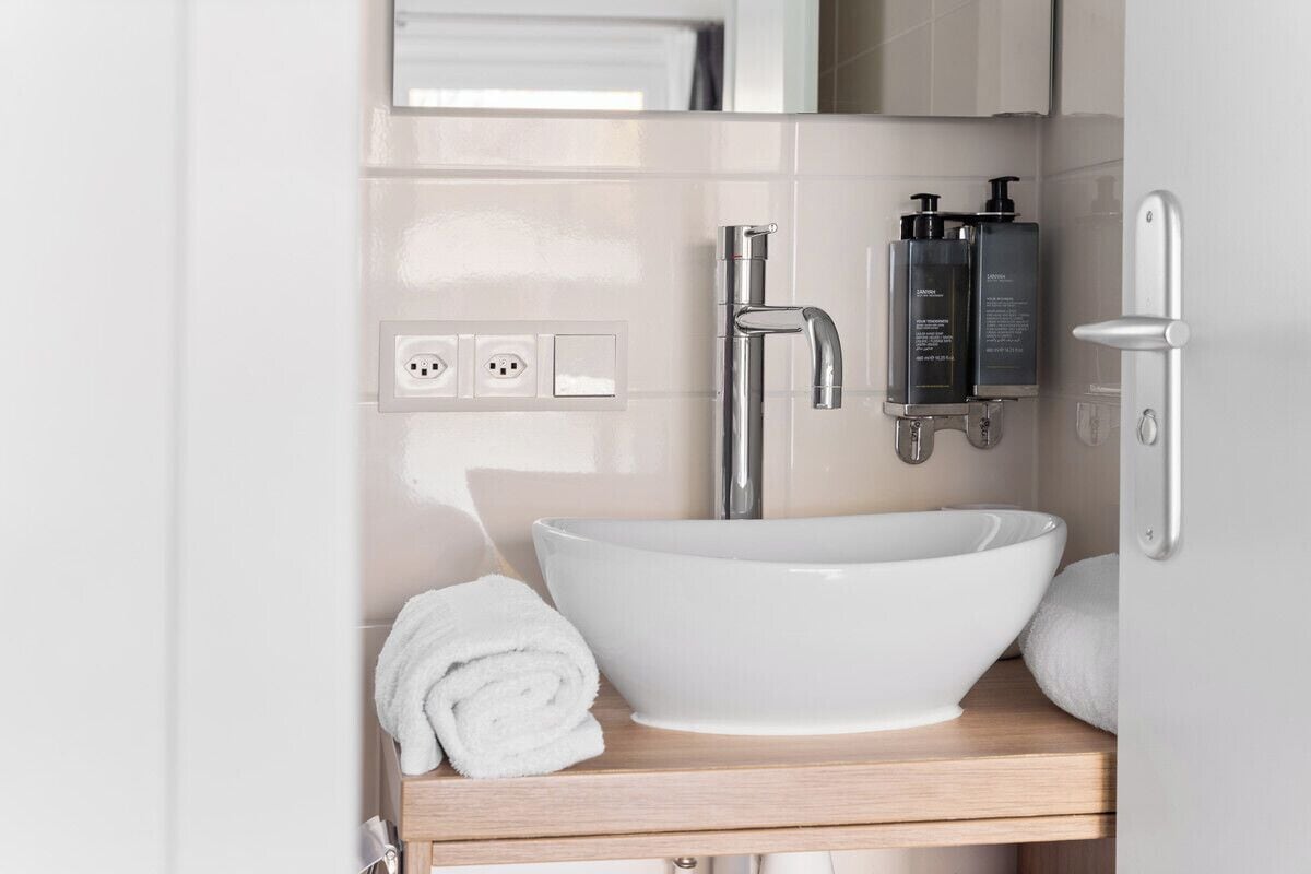 A bathroom with a white sink, a mirror, a towel, and toiletries.