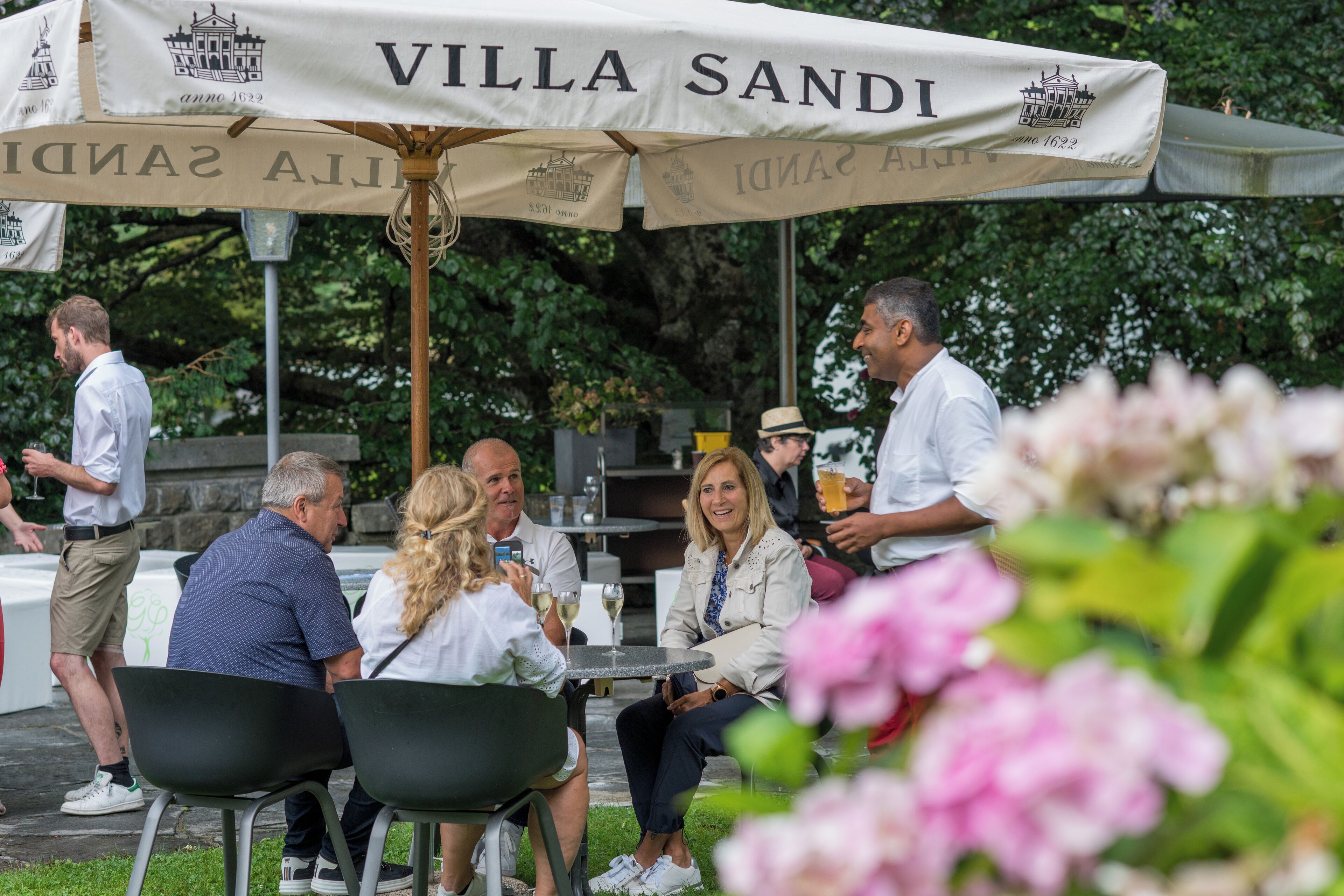 An outdoor seating area with a large umbrella labeled "Villa Sandi".