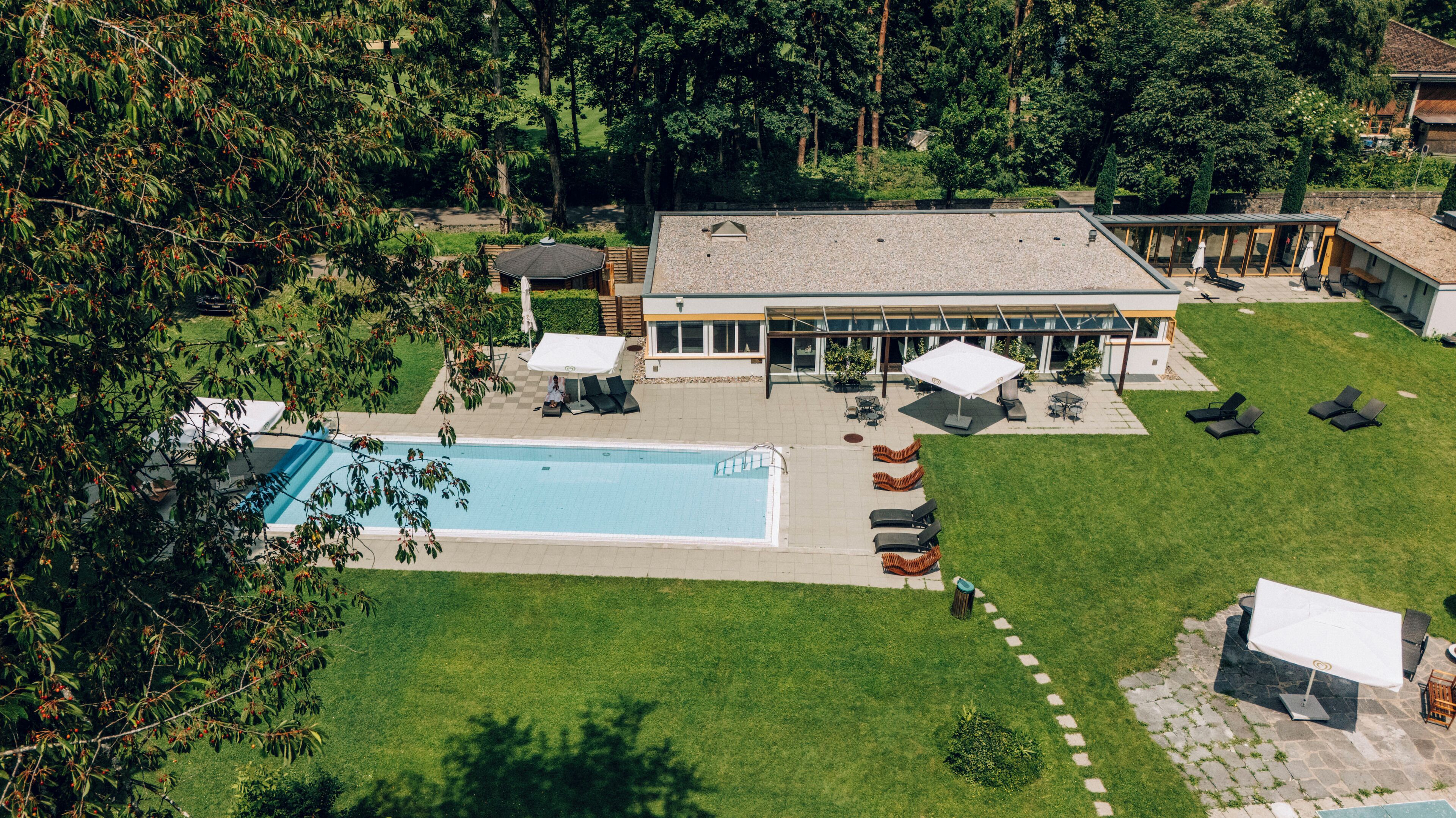 Vista aèria d'una propietat amb piscina, mobiliari exterior i una zona de pati coberta.