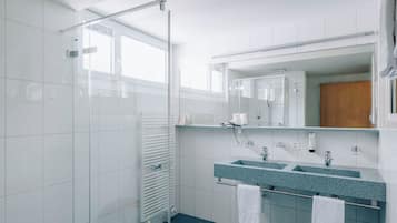 Une salle de bain moderne avec une douche à parois de verre, un meuble-lavabo à deux vasques et un grand miroir.