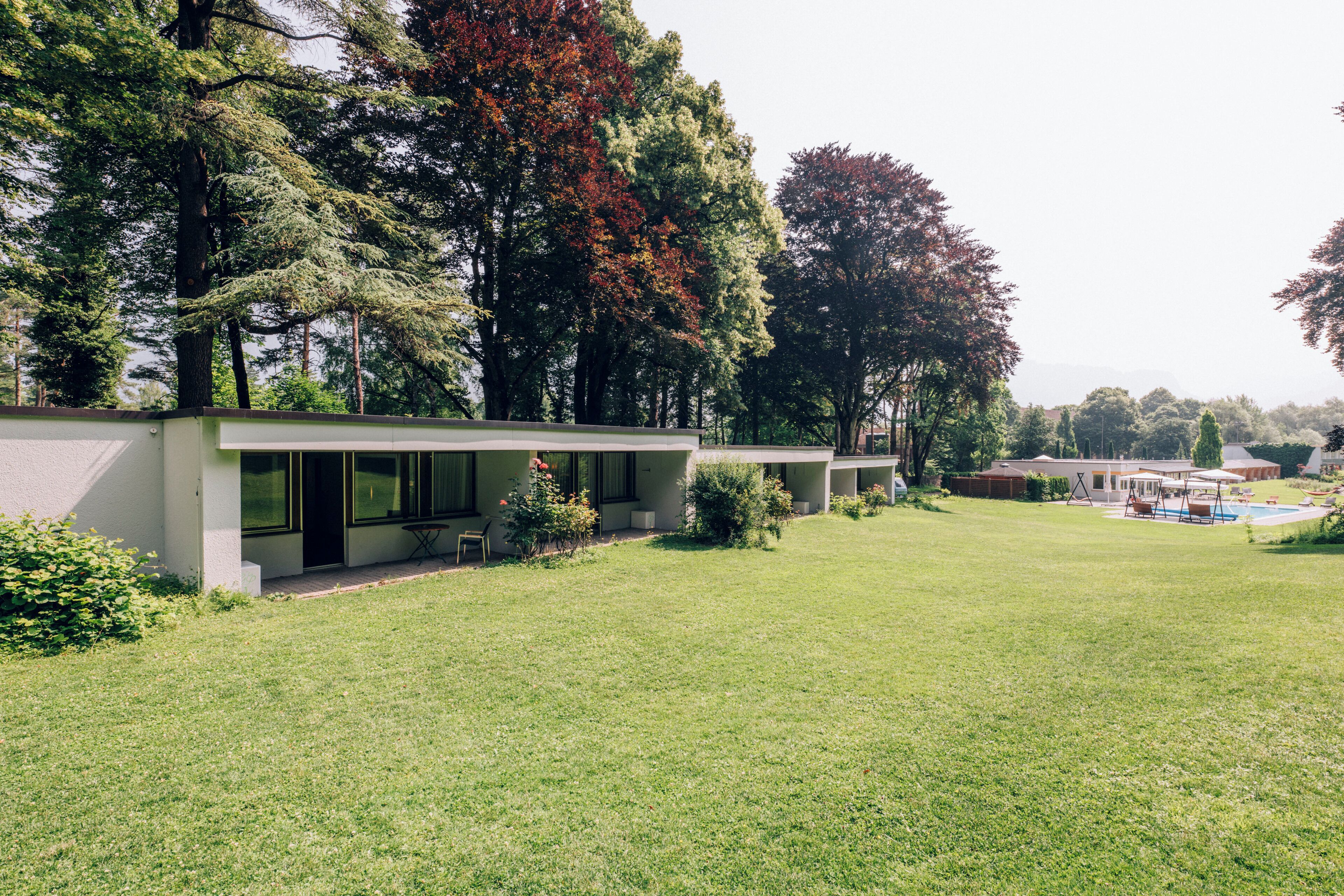 Una casa moderna con un amplio jardín, piscina y un patio cubierto.
