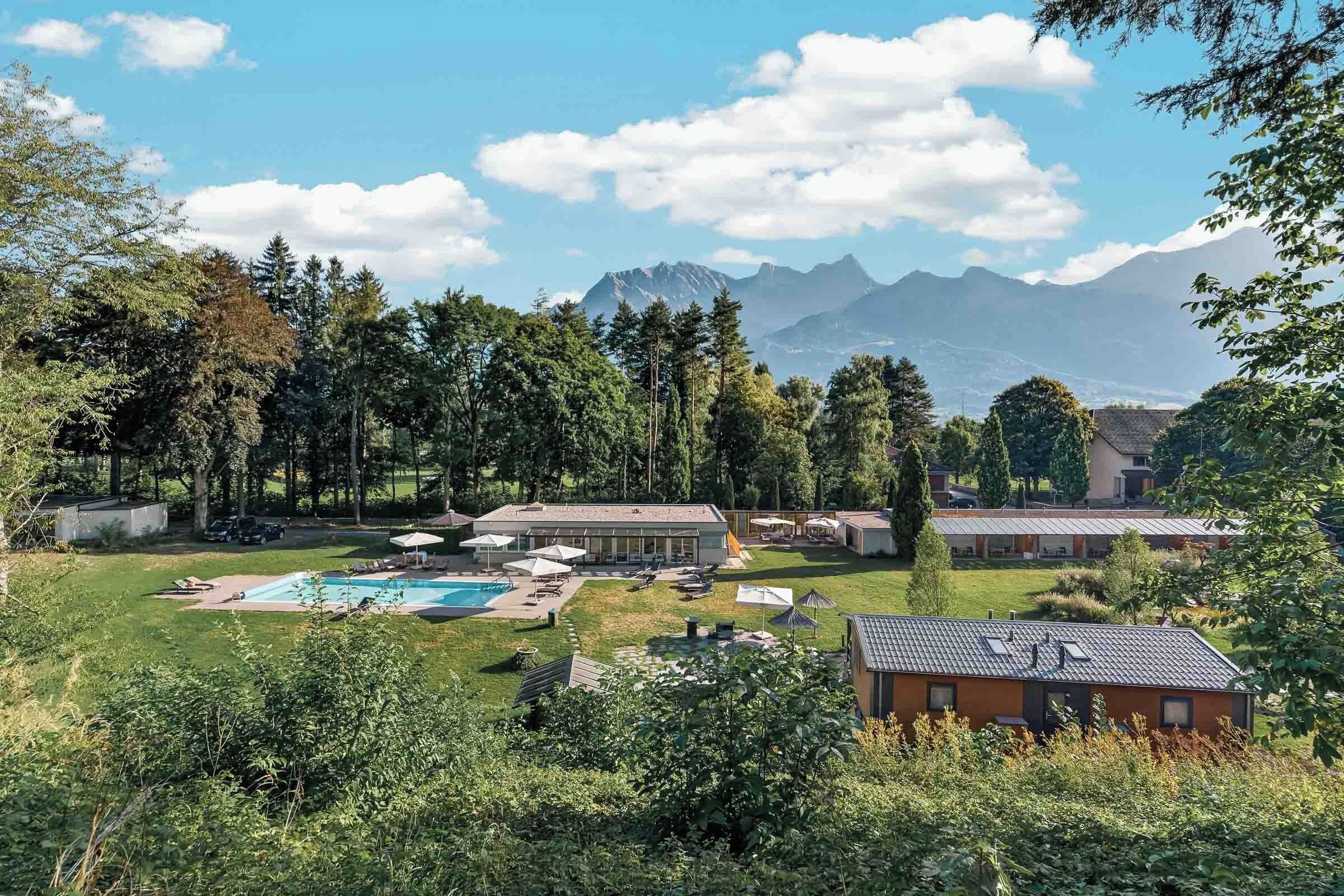 A resort with a swimming pool, lounge chairs, and a view of mountains.