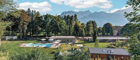 A resort with a swimming pool, lounge chairs, and a view of mountains.