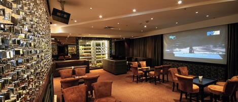 A hotel lobby with a seating area, a projection screen displaying a movie, and a wall of mirrors.